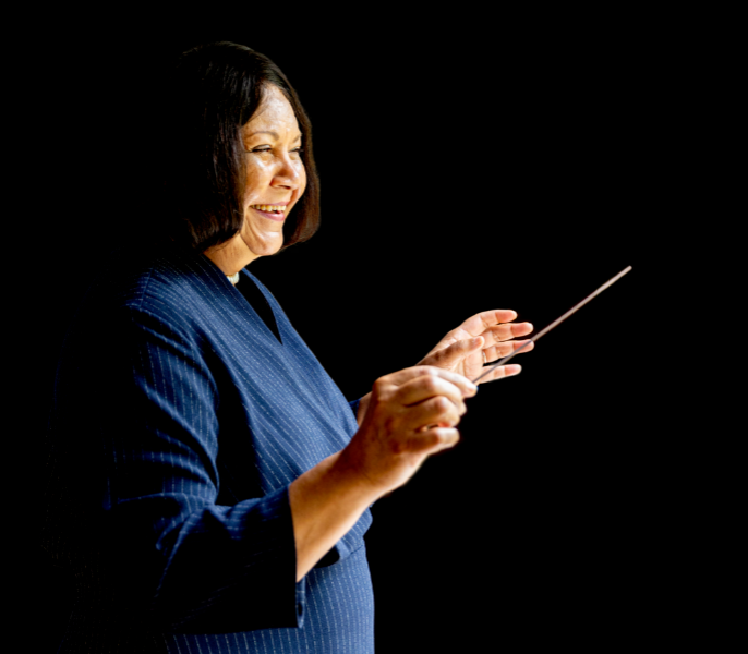 Image of Verna Ruffin smiling with raised arms and holding a conducting baton.